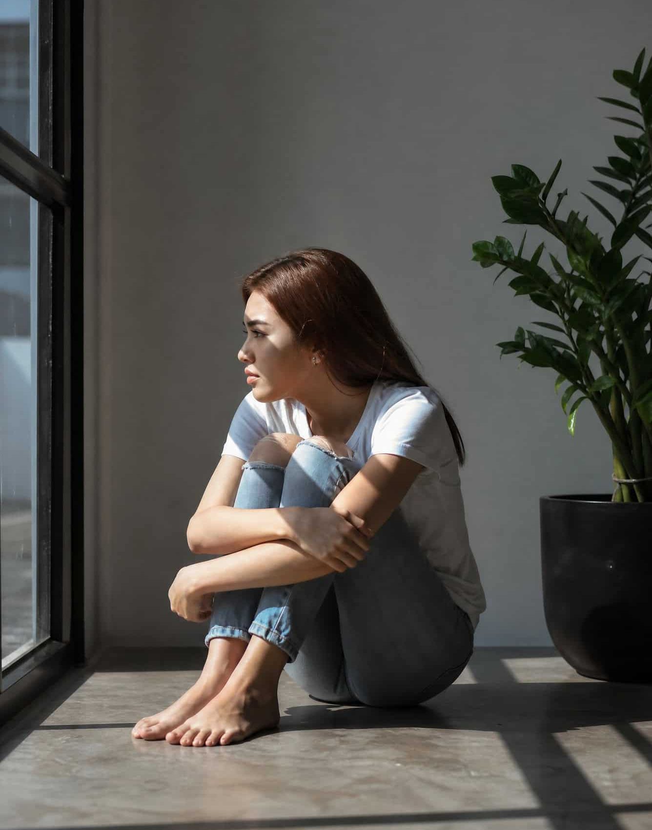 Young woman sitting by a window while seeking hope during addiction treatment in Bowling Green, KY at Redstone Behavioral Health.
