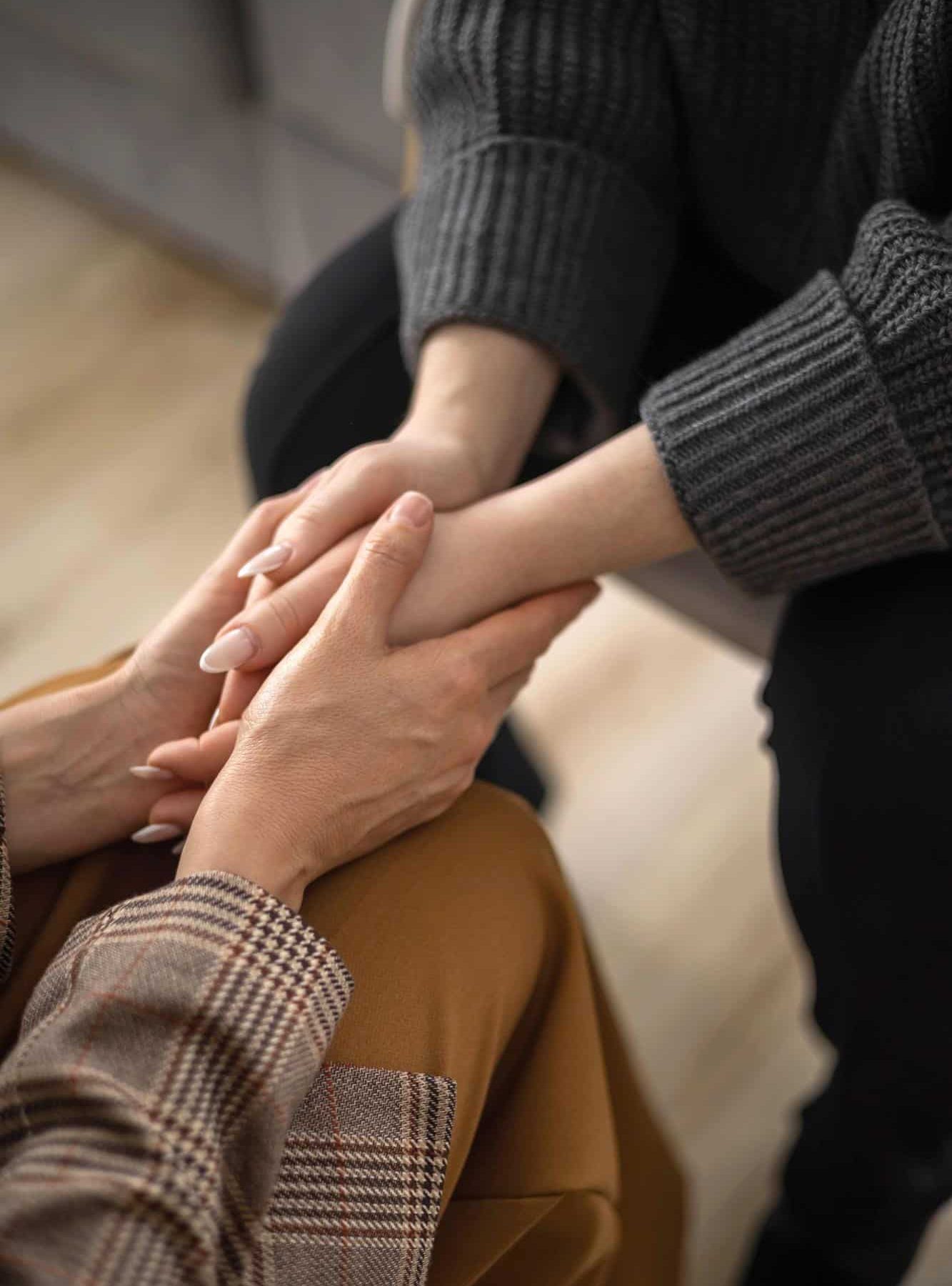 Person holding another person's hands in a supportive gesture during addiction treatment services in Bowling Green, KY at Redstone Behavioral Health.